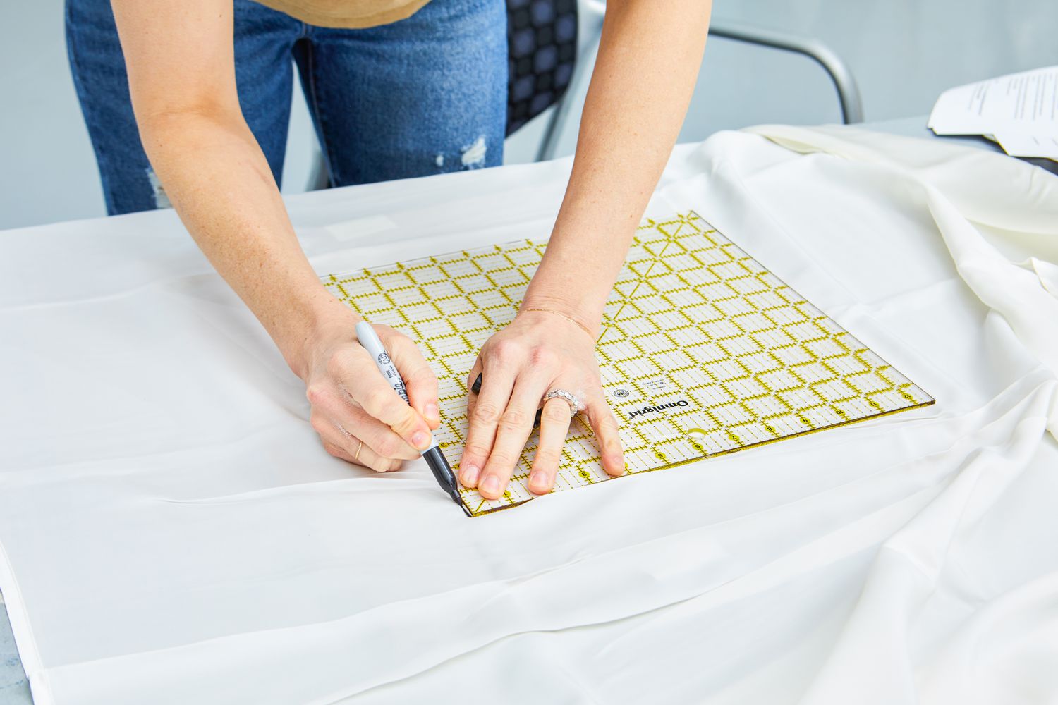 Person marking measurements on the Mulberry Park Silks 22 Momme Silk Sheet Set using a tool