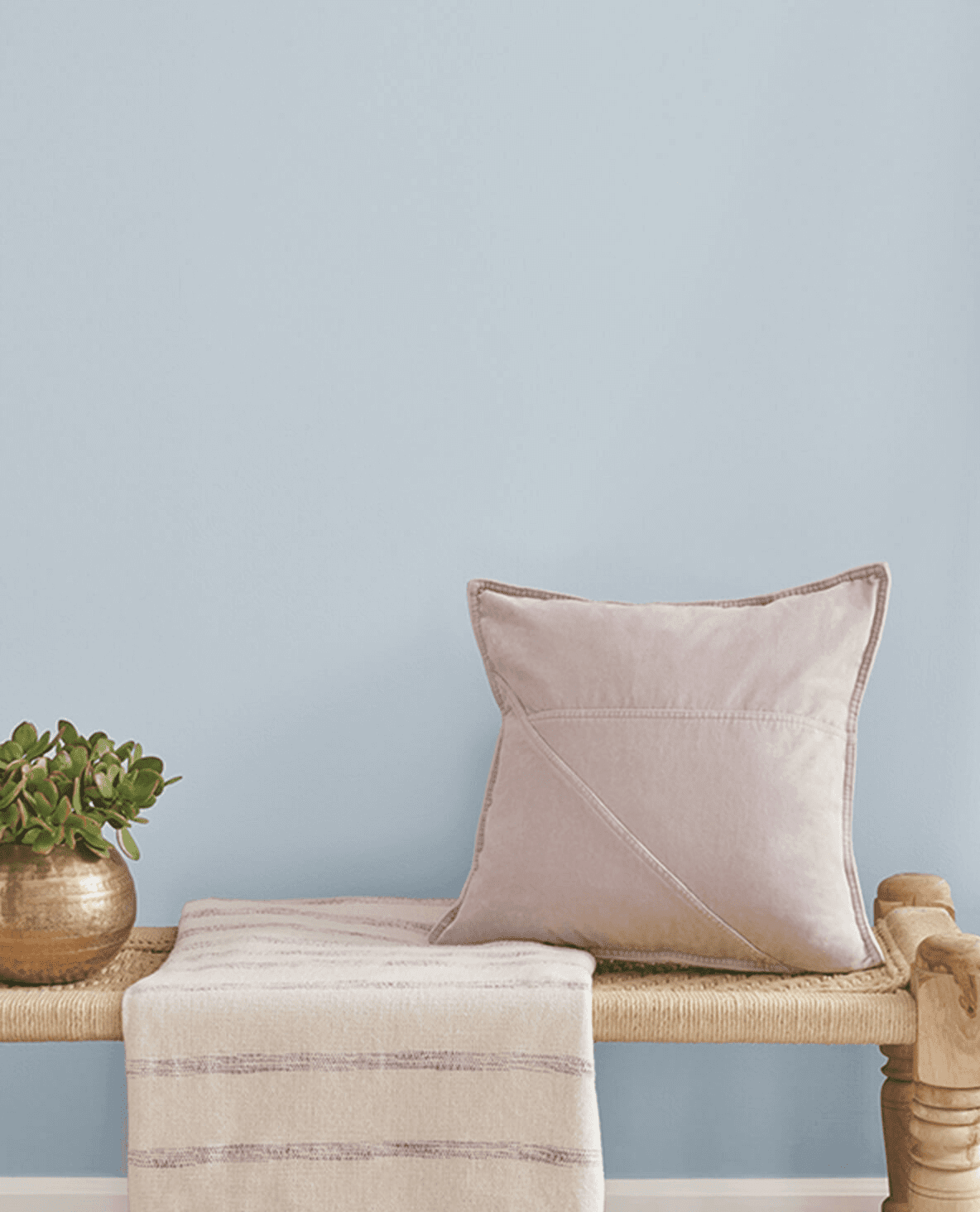 Light Blue paint, Upward by Sherwin-Williams, on wall in front of woven bench with a pillow and blanket