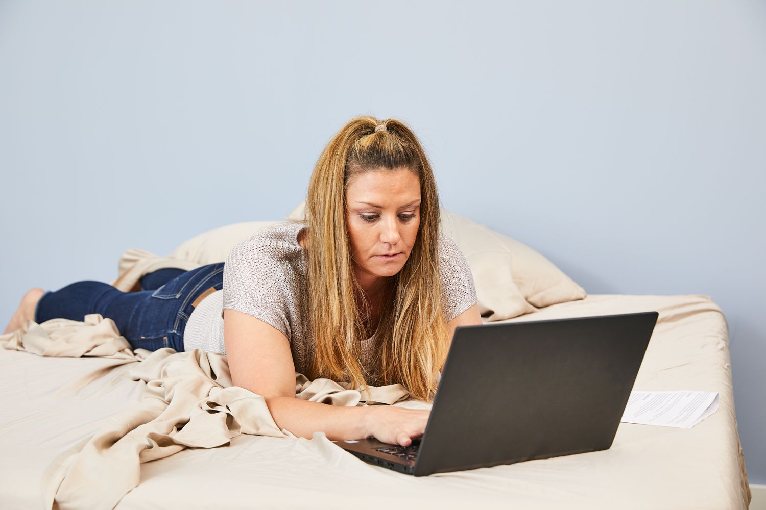 Person lying on a bed made with The Company Store Company Cotton Rayon Made From Bamboo Sateen Sheet Set with a laptop