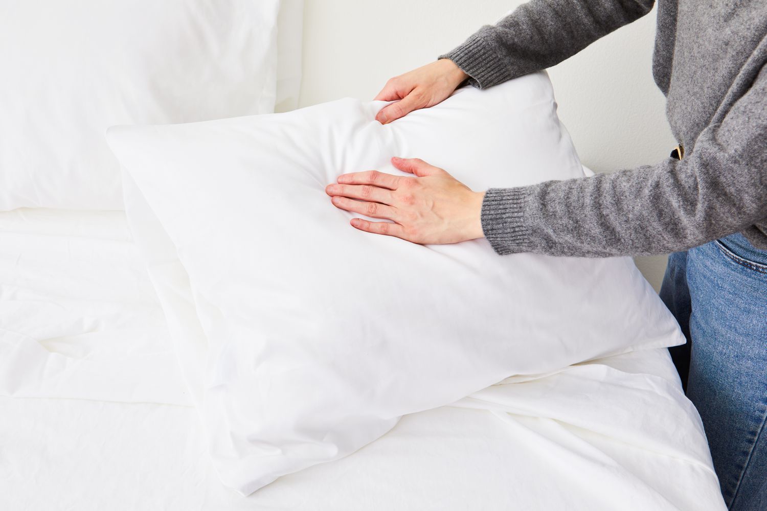 Person touching pillow covered with pillowcase of Boll & Branch Reserve Sheet Set