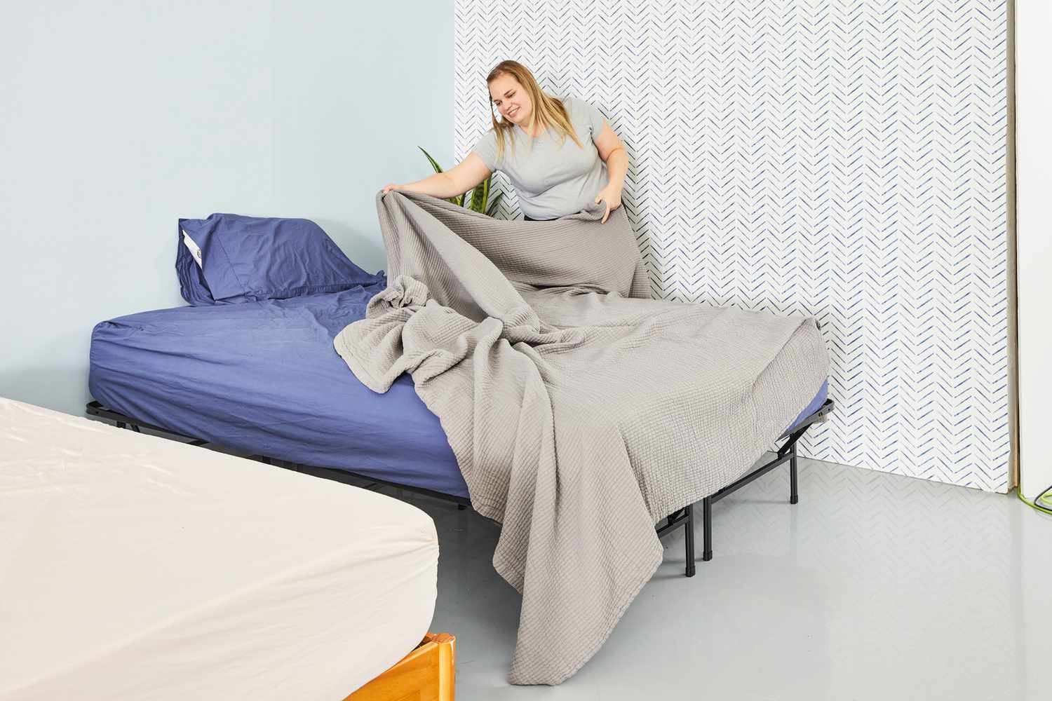 A person making the bed using the Riley Textured Cotton Coverlet