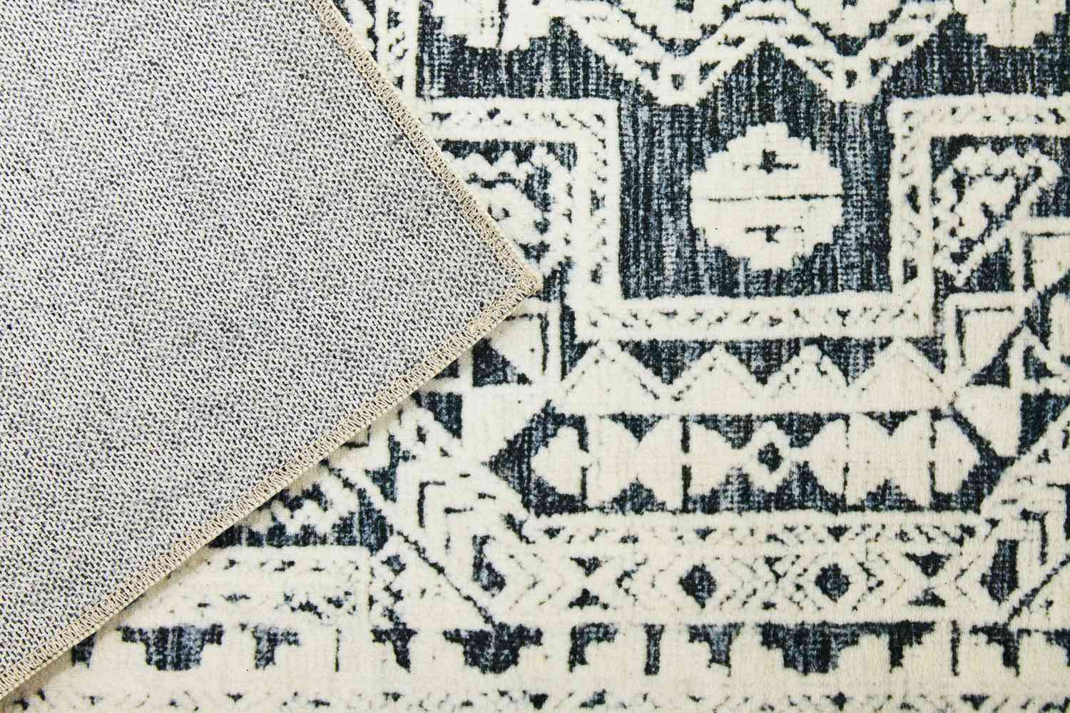 A close up of both sides of the World Market Iman Black And Ivory Persian Style Washable Area Rug