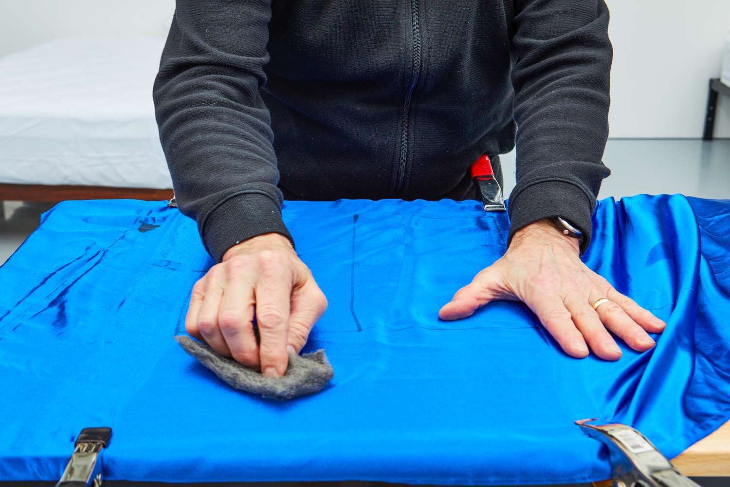 Person rubbing Decolure Satin Sheet with grey cloth during testing